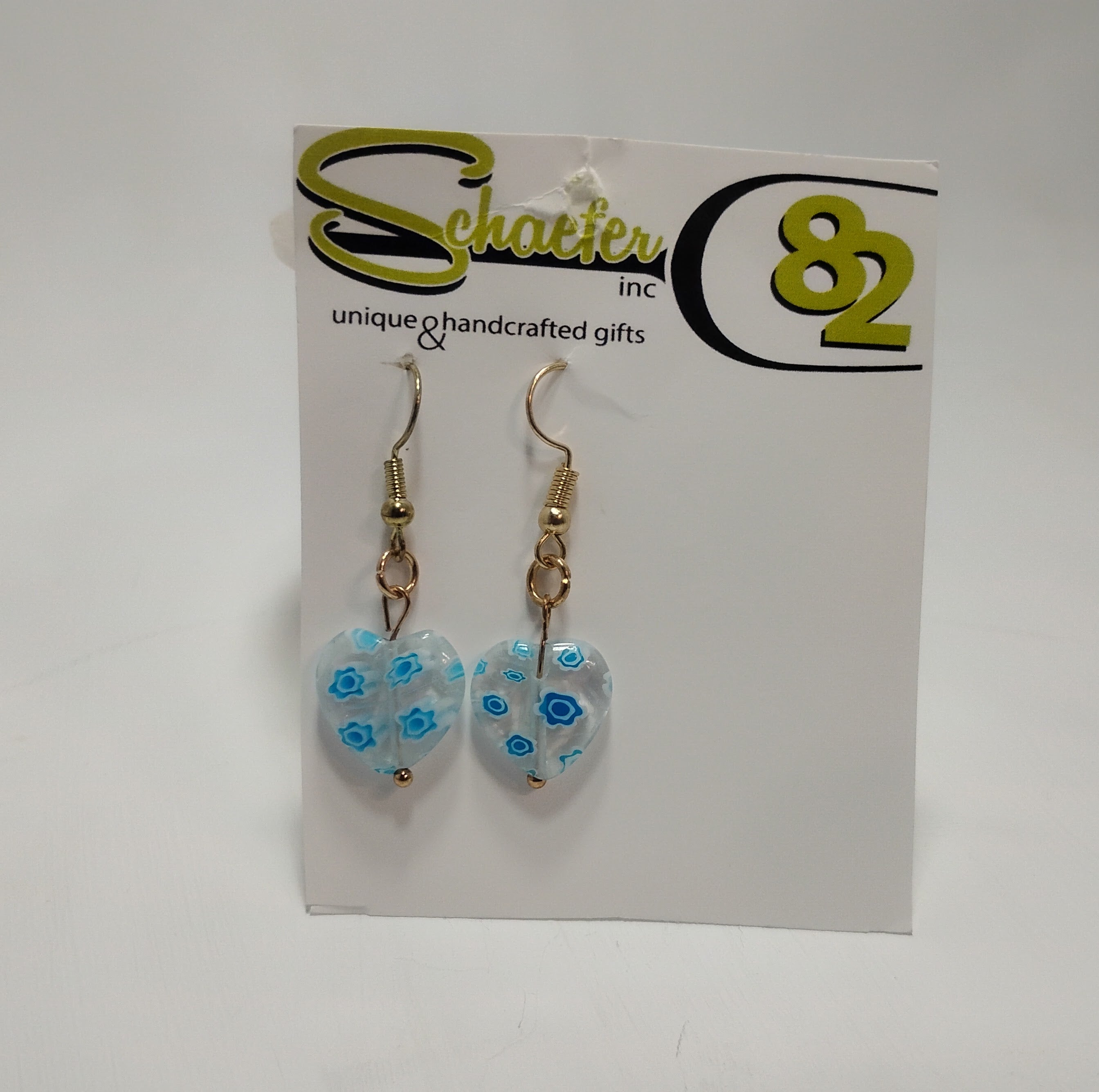 Earrings with a big clear heart that is filled with blue and white flowers.