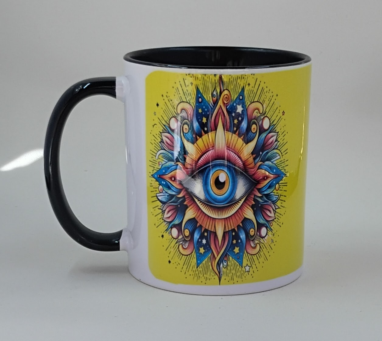 With a yellow background, the colorful evil eye appears to popping off the coffee mug