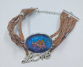 Handcrafted leather bracelet that has the colorful image of a lotus in the center and the word love.