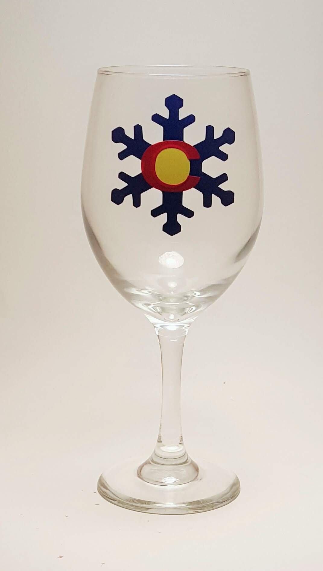 Handcrafted wine glass with a snowflake design, which is made to resemble the Colorado flag.