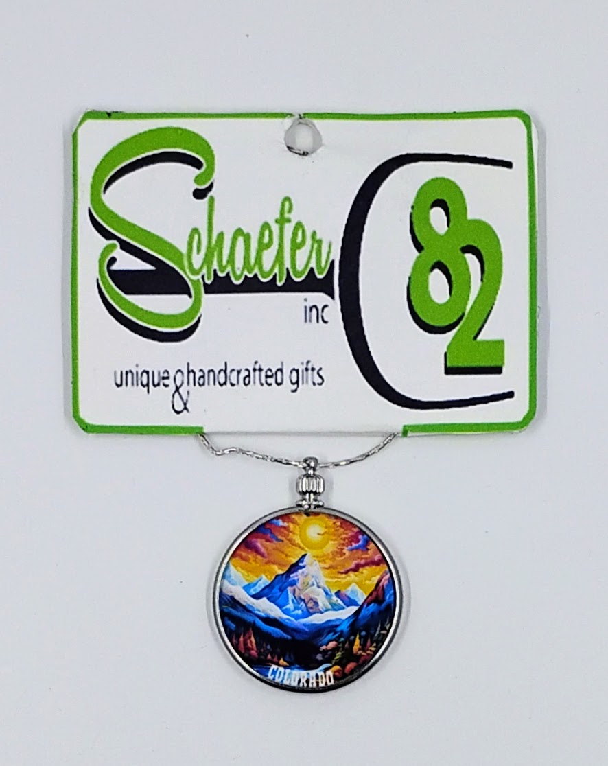 Handcrafted circular necklace with a colorful sunset and beautiful mountains in the background. 