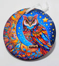 Handcrafted, colorful, celestial ornament, with a bright owl and moon in front of a dark black, star filled, background