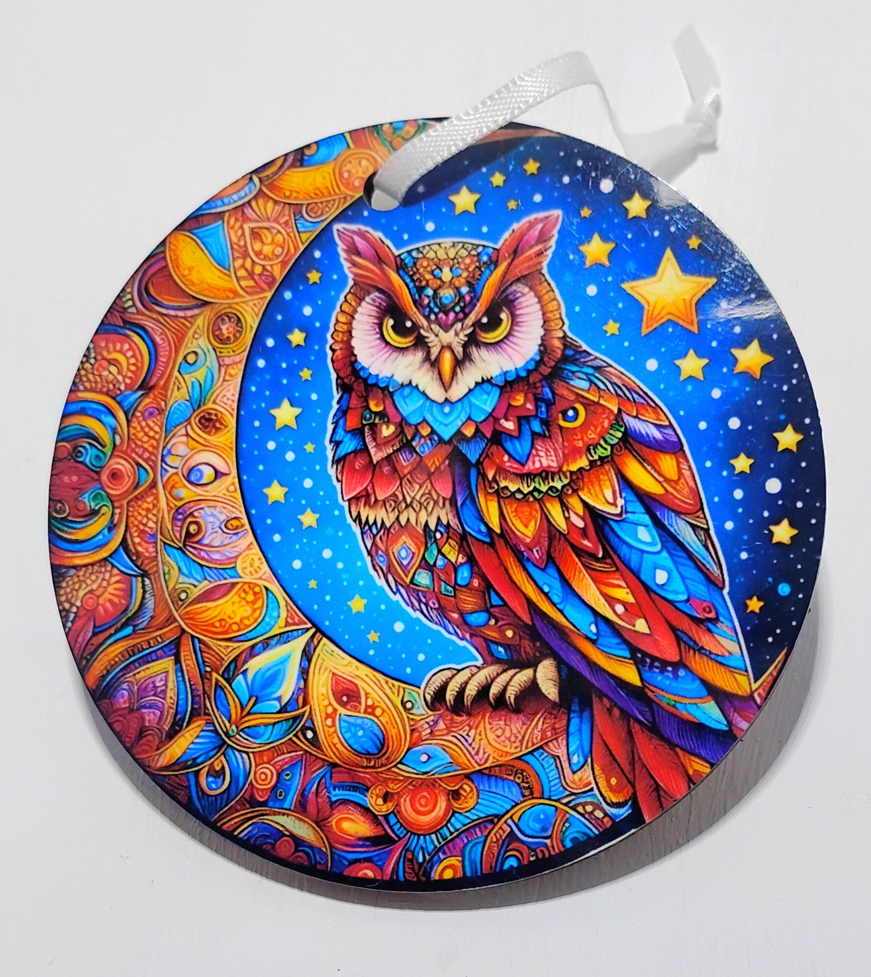 Handcrafted, colorful, celestial ornament, with a bright owl and moon in front of a dark black, star filled, background
