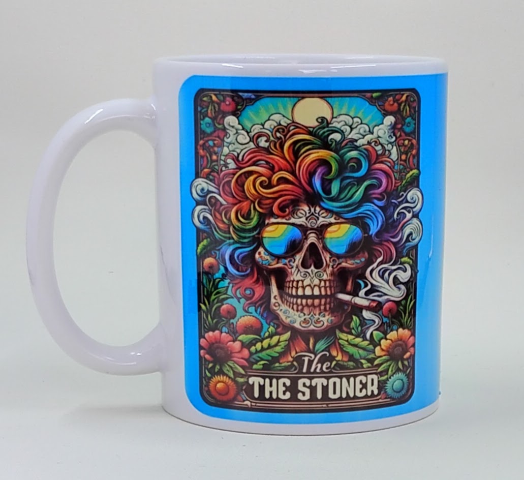 Handcrafted mug with a skeleton with rainbow hair, smoking a joint, and it says "the stoner" on the bottom. Very vibrant and colorful mug