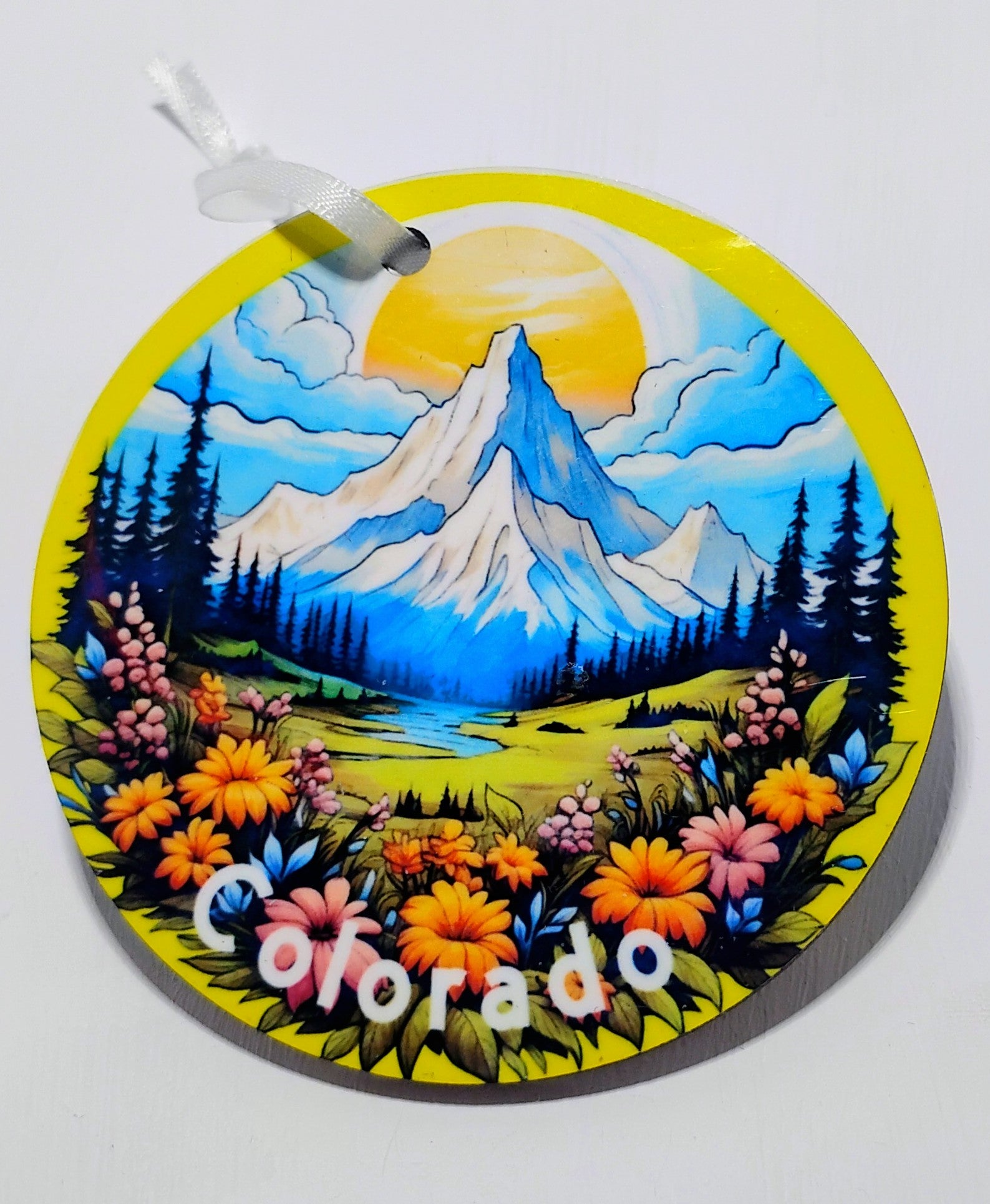 a yellow circular ornament with a beautiful mountain scenery, big sun and a field of flowers