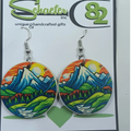 Handcrafted colorful mountain landscape with a green field, river flowing, and an orange sky. 