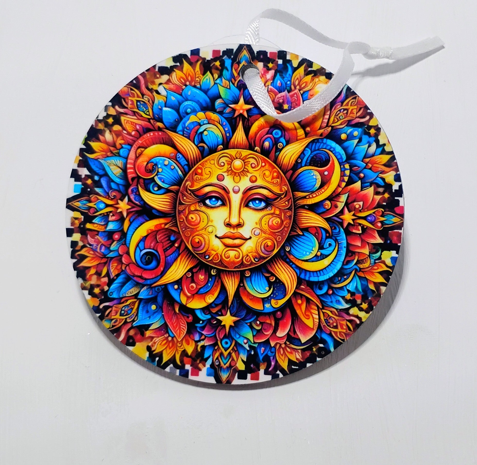 A circular ornament with a beautiful sun on the front, surrounded by so many colors. 