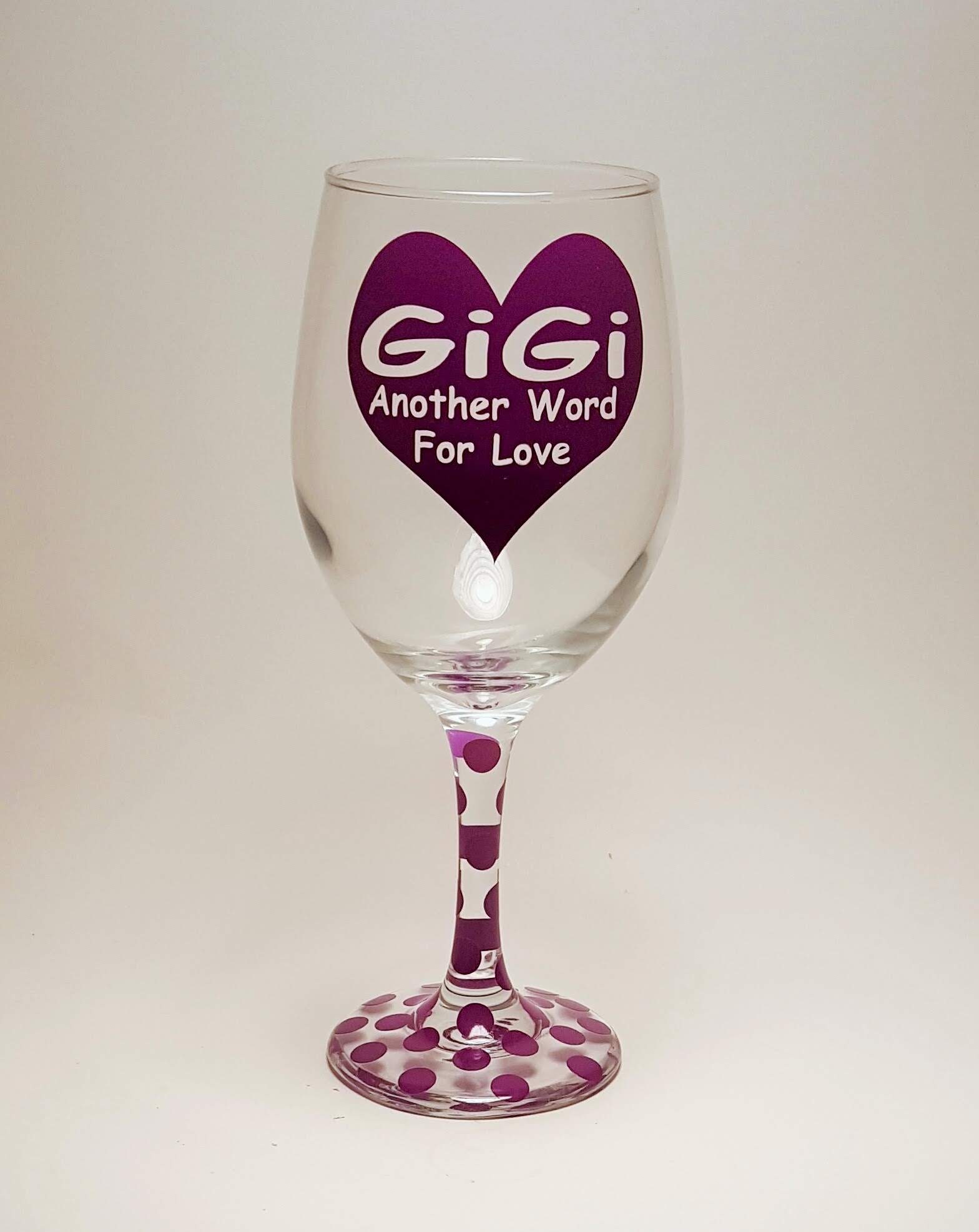 Handcrafted wine glass with a huge purple heart and the quote "Gigi, another word for love "and covered in purple polka dots. 