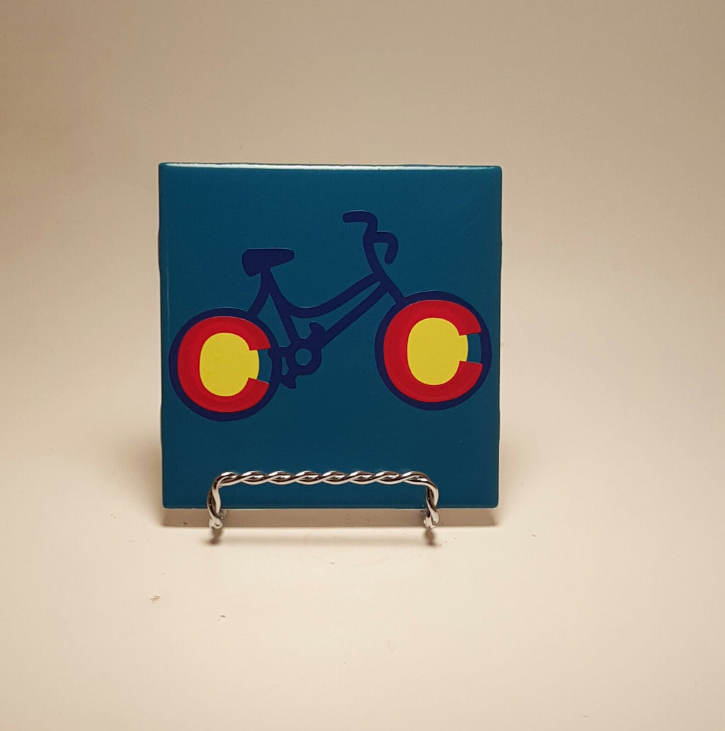 Handcrafted blue coaster with a bike design made to resemble the Colorado flag.