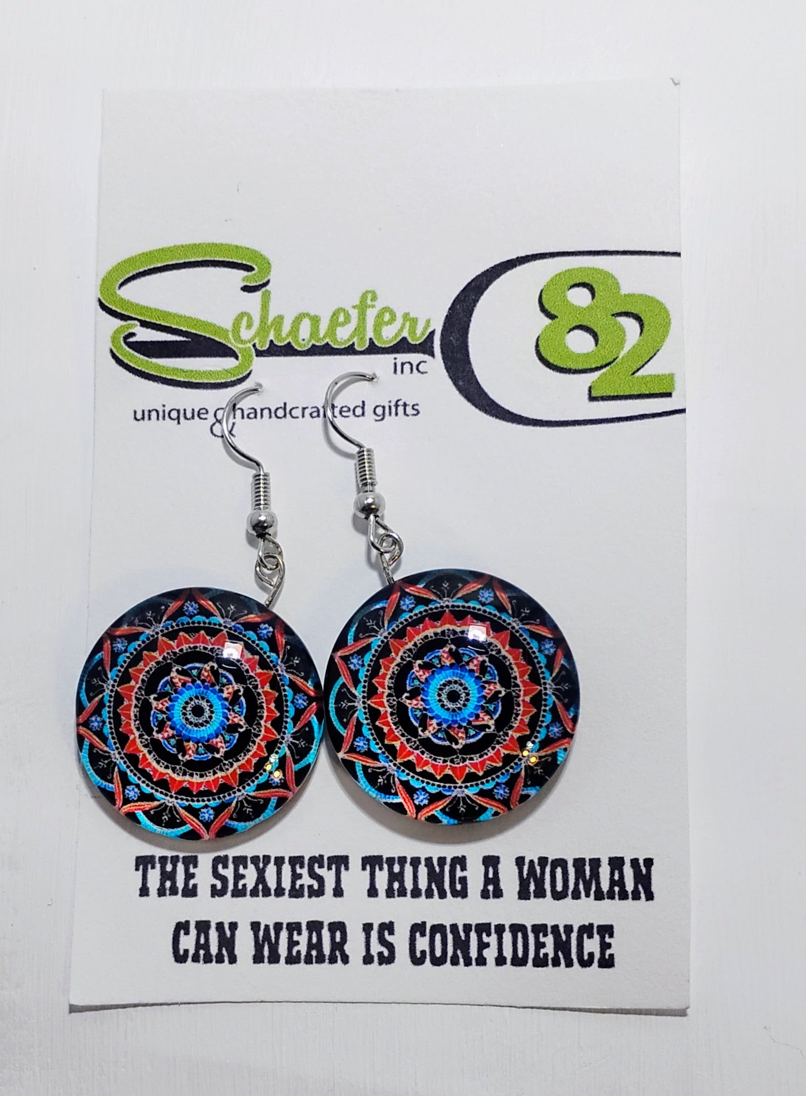 Handcrafted mandala and geometric earrings. The mandala is bright with orange and blue and a black background.