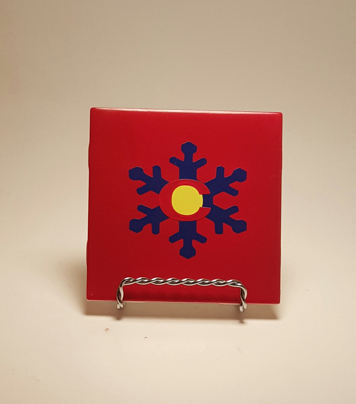 Handcrafted red coaster with a Colorado flag design made out of a snowflake. 
