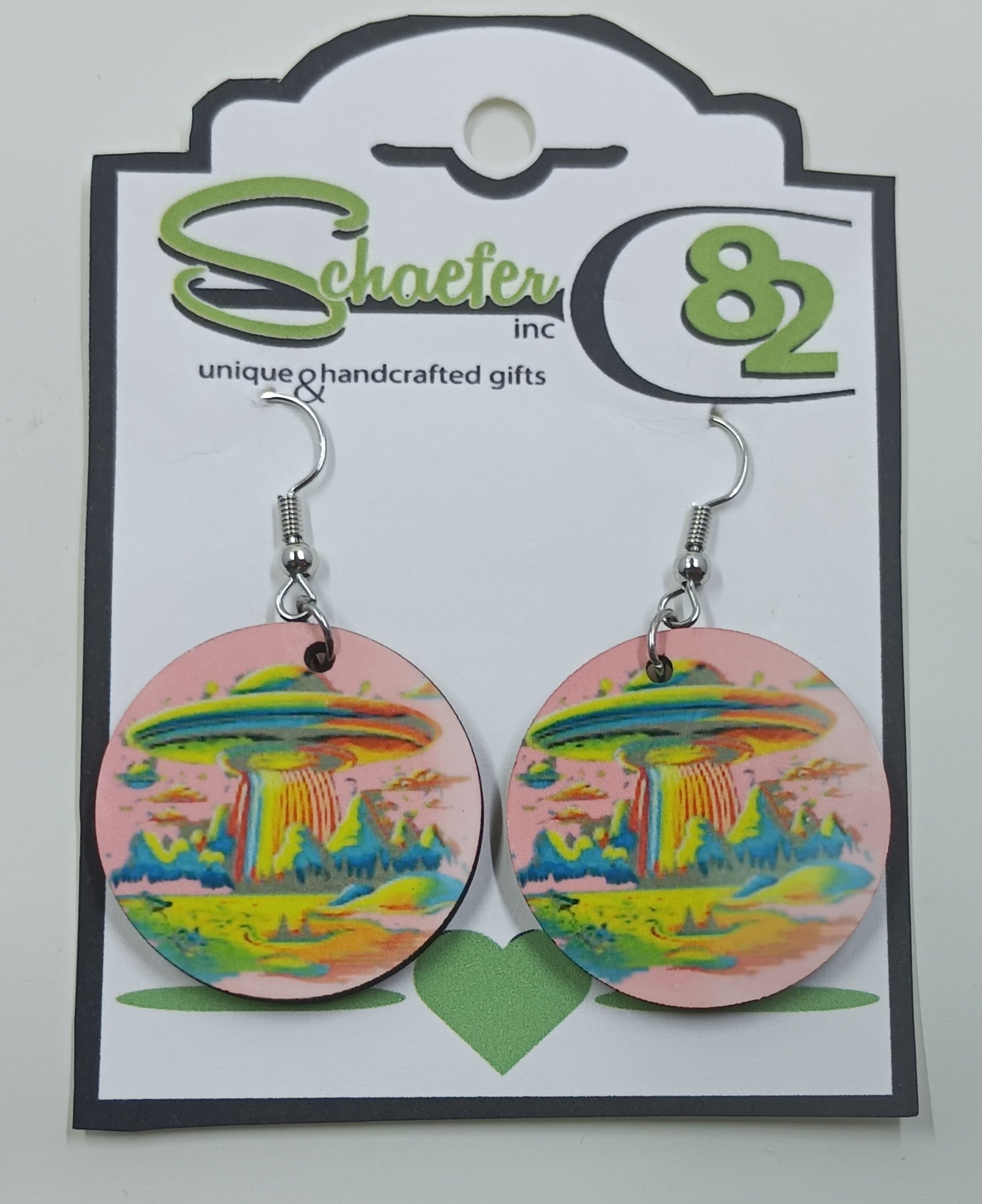 Handcrafted pink earrings with the image of a ufo beaming something up. 