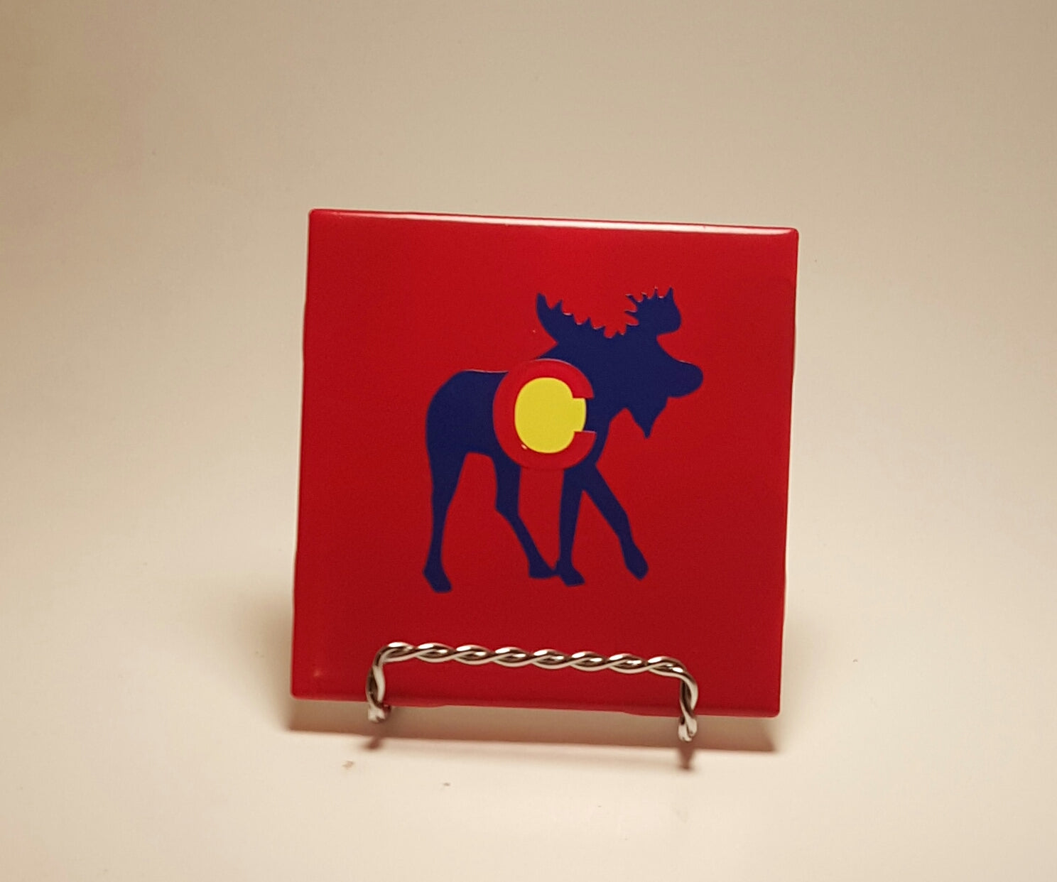 Handcrafted red coaster with a moose design, which is made to resemble the Colorado flag. 
