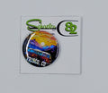 Small round hat pin that is very colorful and has the image of the mountains and a hippy van.