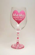 Handcrafted wine glass made with a big heart, filled with the quote "mema, another word for love" in pink.  