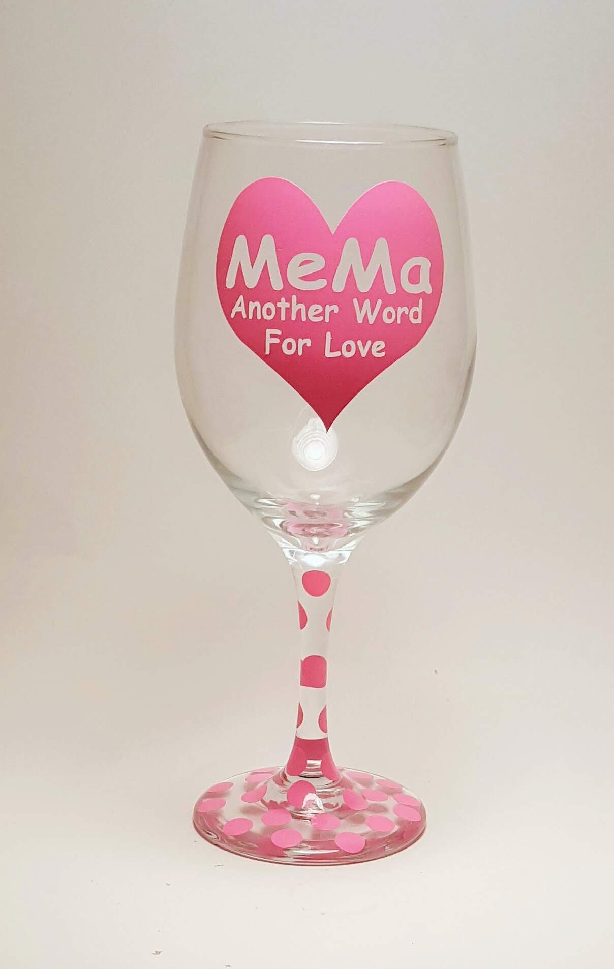 Handcrafted wine glass made with a big heart, filled with the quote "mema, another word for love" in pink.  