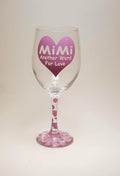 Handcrafted wine glass with a big heart and the quote "Mimi, another word for love" and covered in purple polka dots.