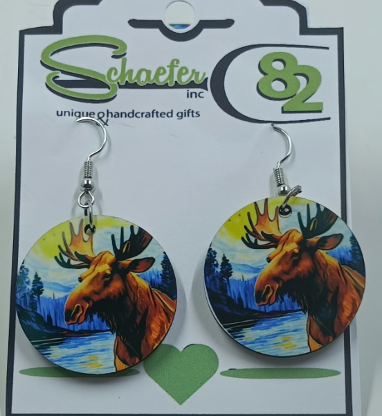 Small circular dangle earrings that has a colorful image of a moose standing by a river and mountains in the background.
