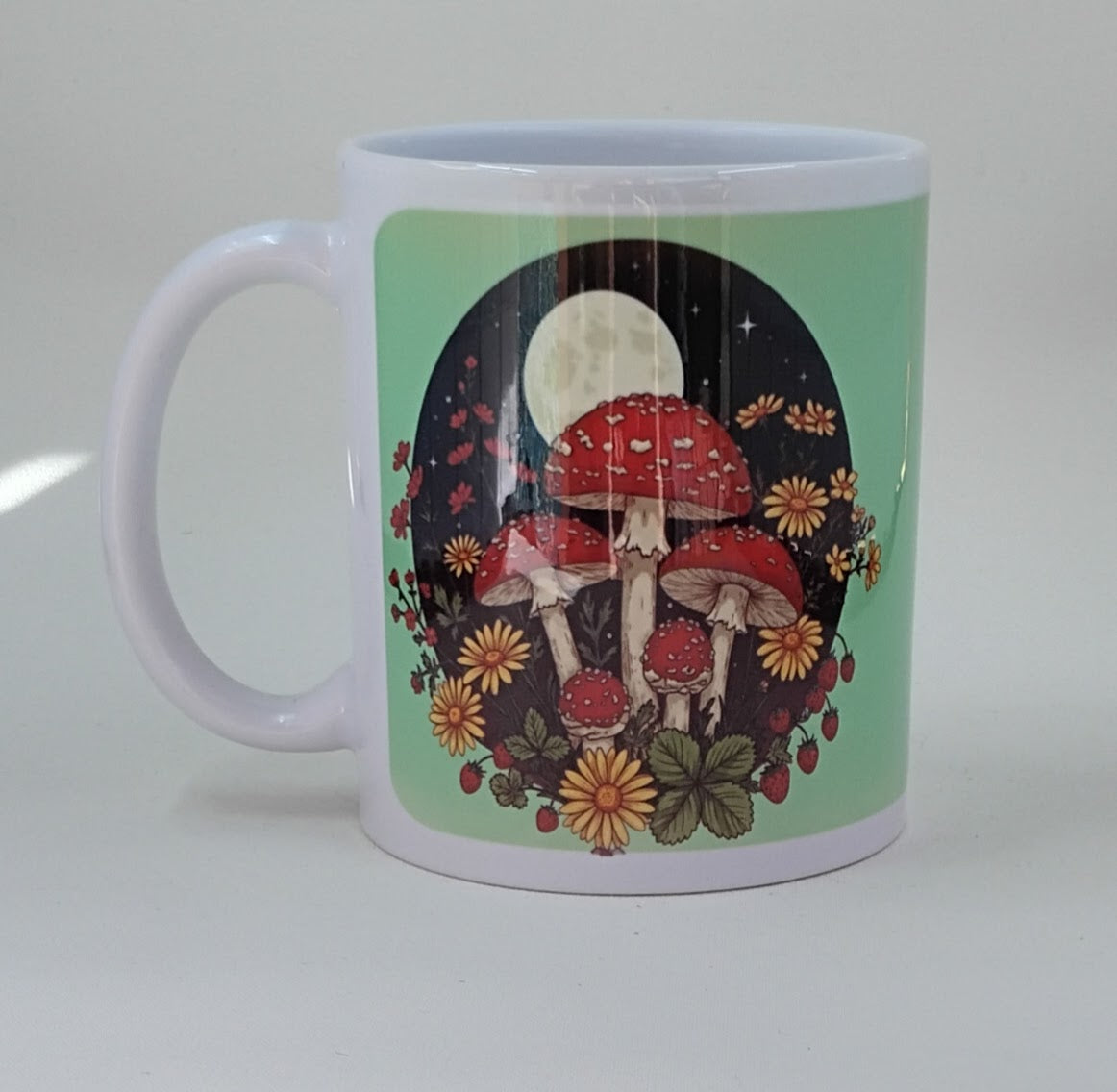 Green coffee mug with a night background showcasing mushrooms, flowers and the moon