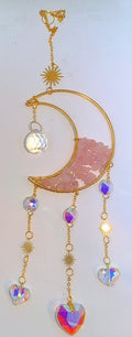 Handcrafted moon suncatcher with pink rose chips filling half the moon and 7 different rainbow forming prism beads