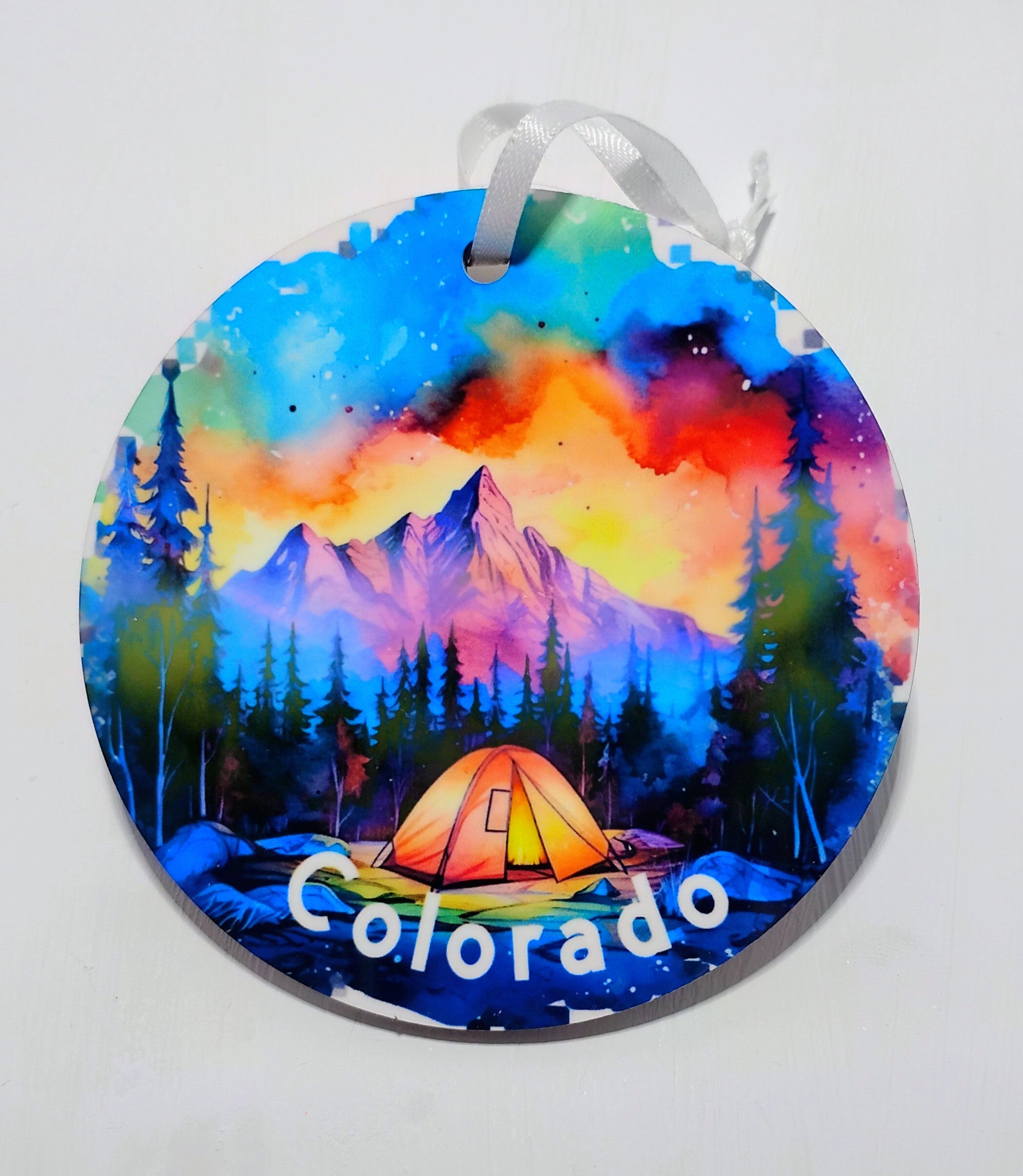 Very colorful circular ornament with a beautiful mountain scenery, a colorful sunset and tent for camping front and center