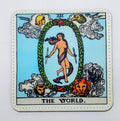 Handcrafted white tarot card with the tarot image for the world, which is a naked women in a wreath, surrounded with four characters. 