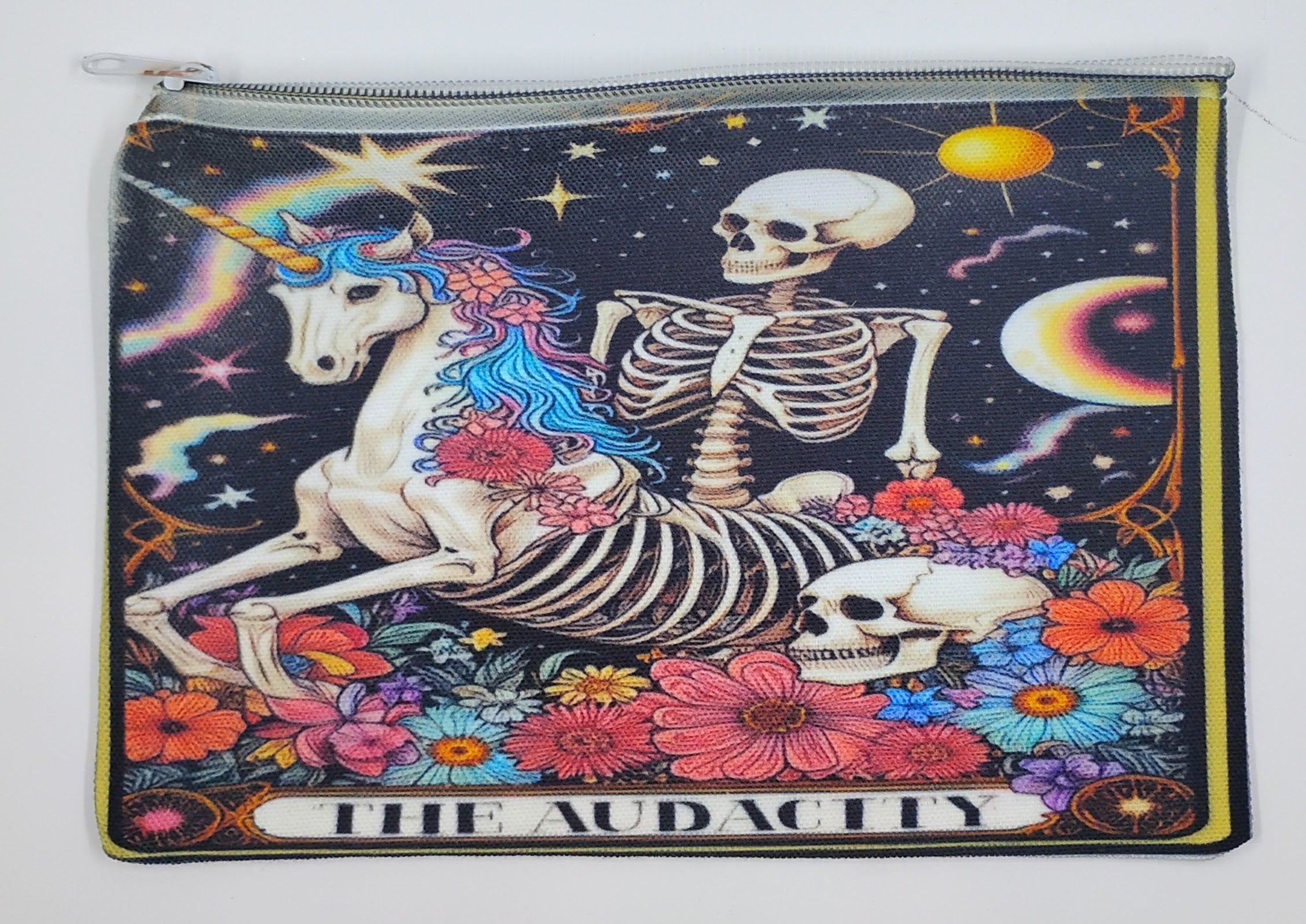 Handcrafted tarot inspired zipper bag with a skeleton riding a colorful unicorn, surrounded by colorful flowers and a night sky. The bottom says "the audacity".