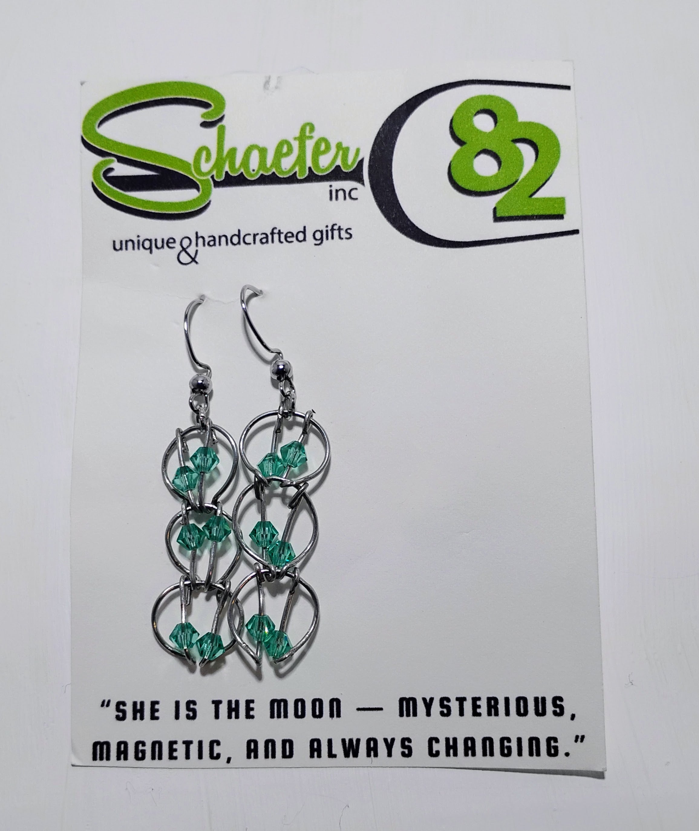 Pair of silver hoop earrings that have teal accents throughout. 