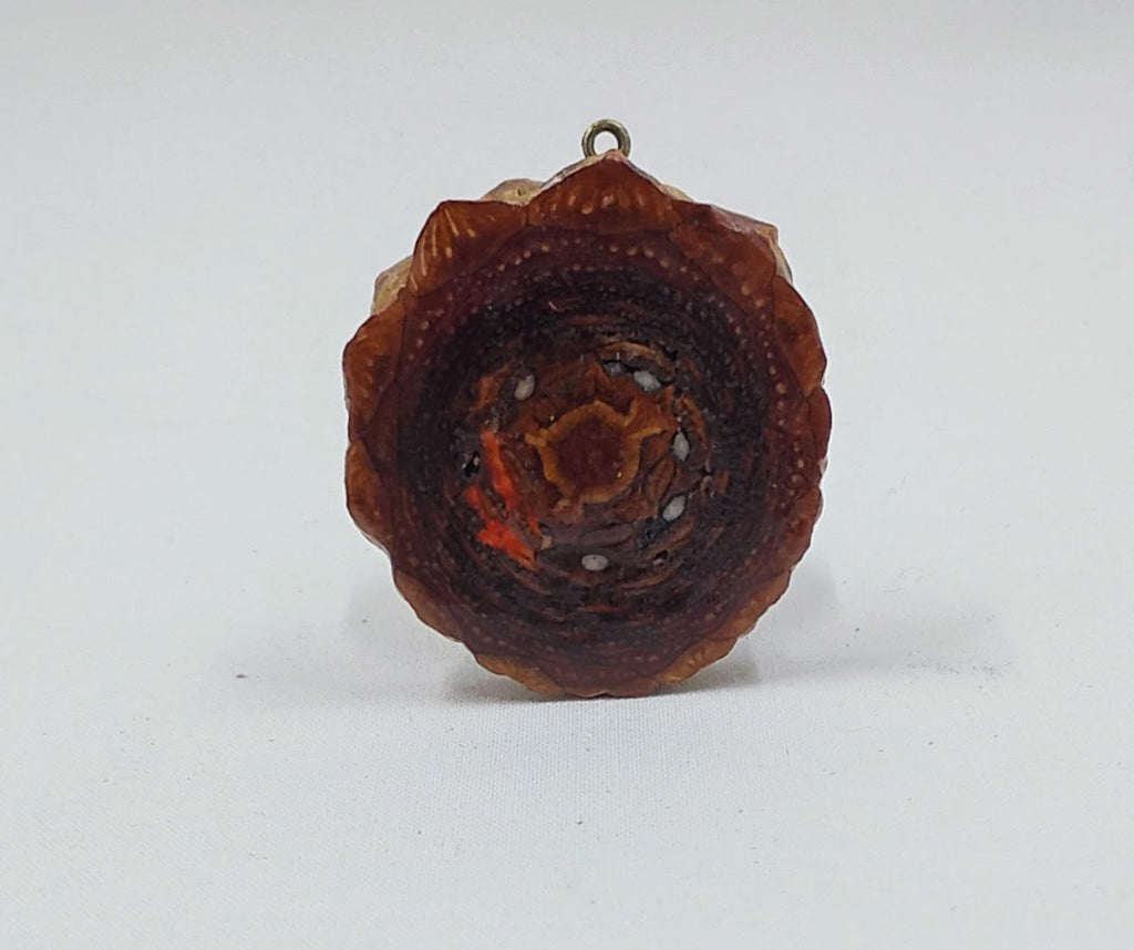 Third eye pinecone pendant with orange accents and is showing the back of the pendant