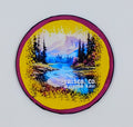 Pink circular magnet with a watercolor mountain scenery and river  with  a yellow background. 